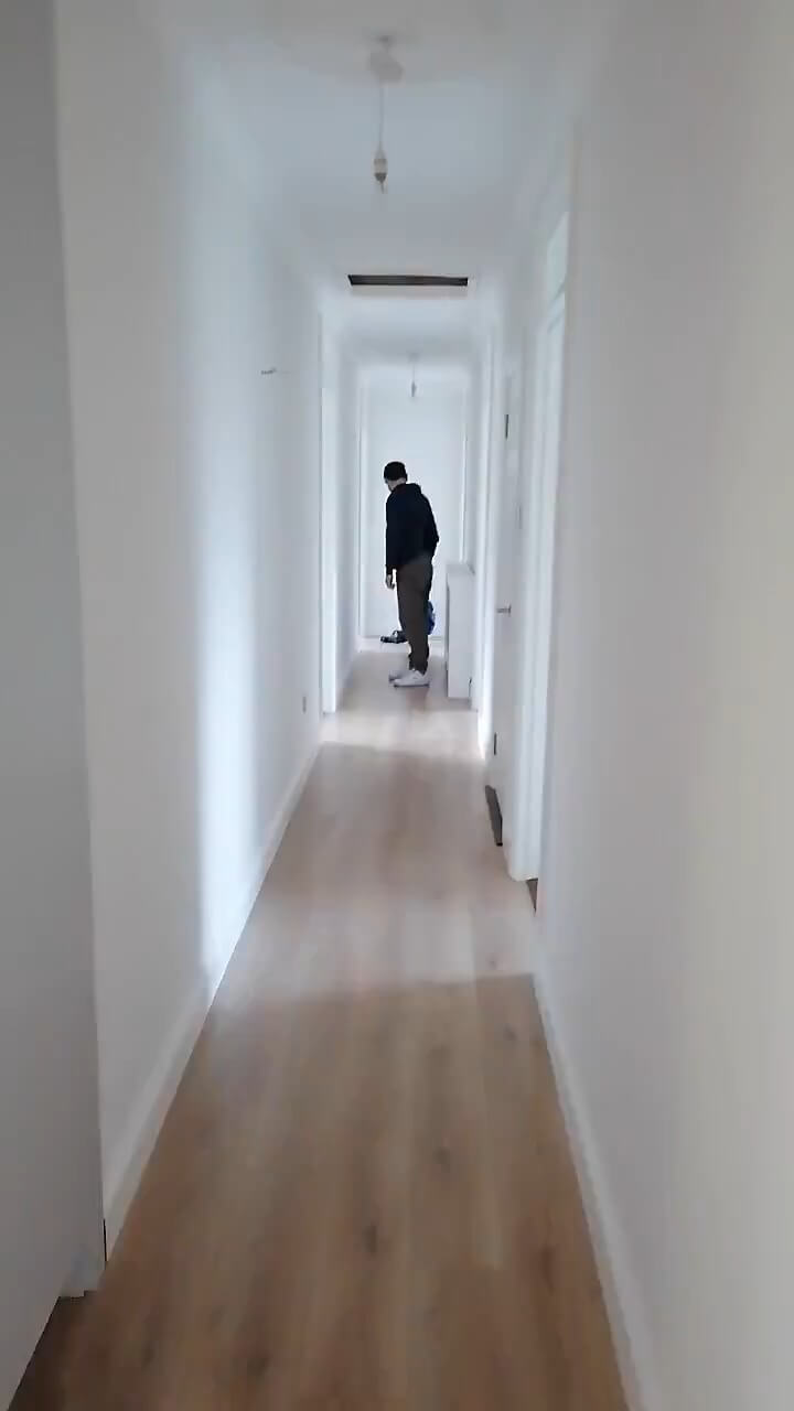 a long hallway in a bungalow with plain white walls